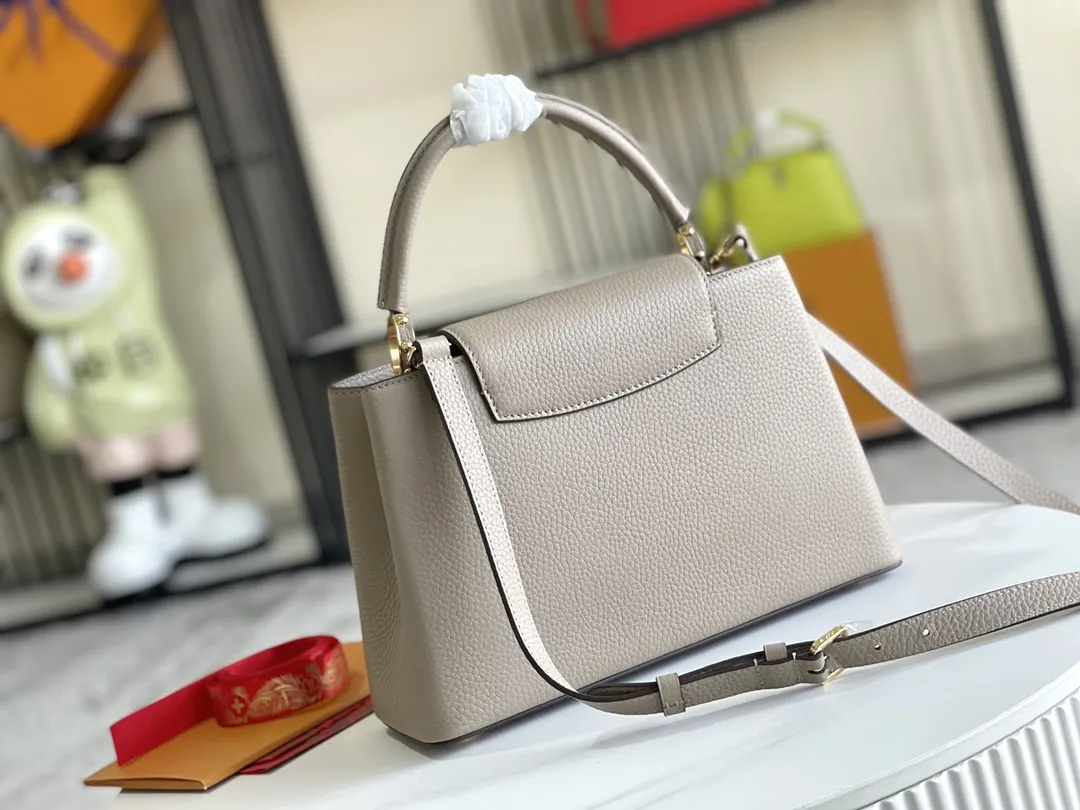 （163 芯片）特级配全套包装💰P1050【特级精品原厂皮💋 M94428 大象灰中号金扣】 第一家路易威登门店开在巴黎的嘉布遣街上，Capucines手袋与品牌一样经久不衰，可以为任何造型带来时尚的精致感。全粒面Taurillon皮与稀有宽纹蟒蛇皮结合，打造出一款奢华的手提包，各种传统的细节是手袋的亮点：LV首字母，独特的边环，翻盖上精细的Monogram花朵。配有顶部手柄、可脱卸包带与独特包盖，多种背携风格，适应不同造型或心情。 &diams;️进口荔枝纹牛皮 &diams;️原厂全钢拉丝五金 尺寸：31.5 x 20.0 x 11.0 cm