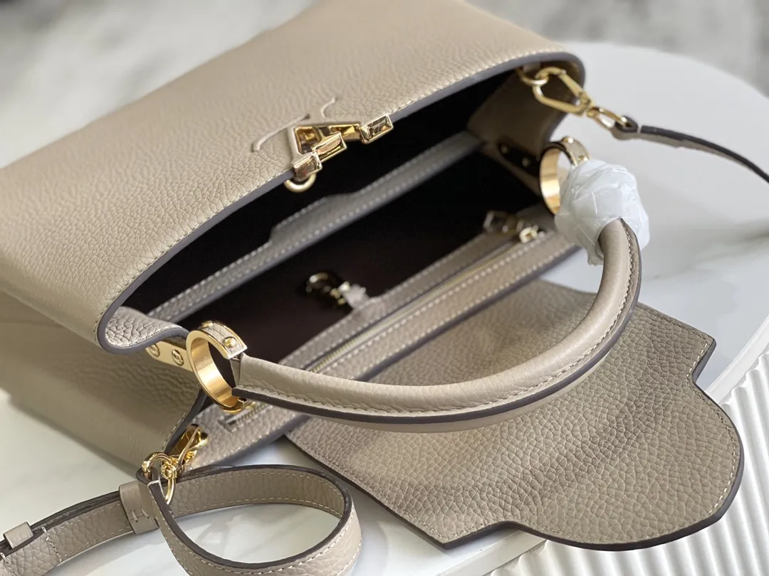 （163 芯片）特级配全套包装💰P1050【特级精品原厂皮💋 M94428 大象灰中号金扣】 第一家路易威登门店开在巴黎的嘉布遣街上，Capucines手袋与品牌一样经久不衰，可以为任何造型带来时尚的精致感。全粒面Taurillon皮与稀有宽纹蟒蛇皮结合，打造出一款奢华的手提包，各种传统的细节是手袋的亮点：LV首字母，独特的边环，翻盖上精细的Monogram花朵。配有顶部手柄、可脱卸包带与独特包盖，多种背携风格，适应不同造型或心情。 &diams;️进口荔枝纹牛皮 &diams;️原厂全钢拉丝五金 尺寸：31.5 x 20.0 x 11.0 cm